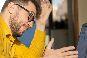 The unshaven man in glasses with laptop at home.