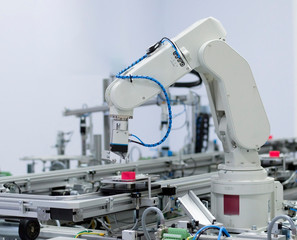 Focus on robot arm's gripper. Industry 4.0 concept; artificial intelligence in smart factory. Robot picks up the product from automated car on the manufacturing line. Selective focus.
