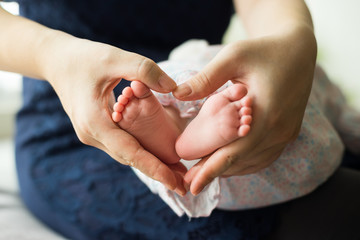 Baby feet in mother's hand with love shape