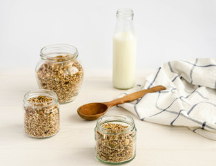 Homemade muesli in a glass jar and a bottle of milk on a white background