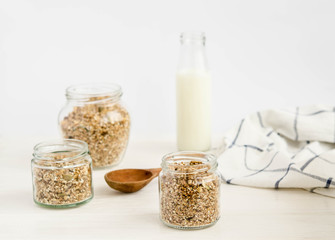 Homemade muesli in a glass jar and a bottle of milk on a white background