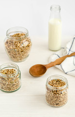 Homemade muesli in a glass jar and a bottle of milk on a white background