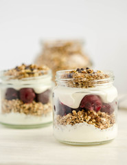 Homemade granola with cherry, yogurt in a glass jar