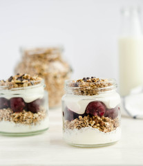 Homemade granola with cherry, yogurt in a glass jar