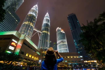 Fotobehang Young woman traveler traveling and looking colorful fountain show of Petronas Twin Towers at center business district of Kuala Lumpur Malaysia. © Travel man