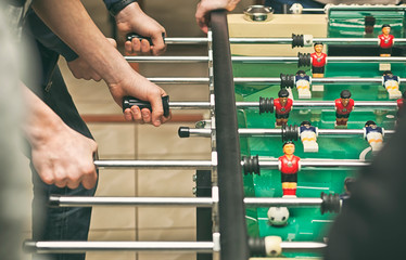Guys are  playing table soccer indoor