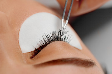 Woman with long eyelashes in beauty salon. Lashes extension procedure close up. Cosmetics and makeup.
