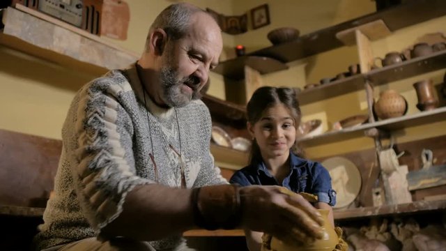 Pottery workshop. Grandpa teaches granddaughter pottery