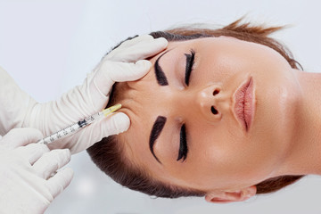 Beauty Procedure. Portrait Beautiful Young Woman Receiving Hyaluronic Acid Injection. Closeup Of Hands In Gloves Holding Syringe Near Attractive Female Face. Facial Beauty Injections. Facelift