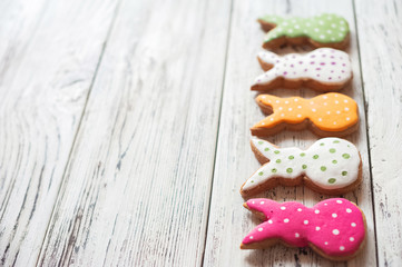 Painted ginger Easter gingerbread, colorful eggs on a wooden textural white background close-up and copy space. Easter greeting card concept