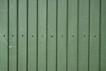 Fototapeta premium Forest green wood panel fence, with line of screws going straight across the middle. Wood has textured vertical panels