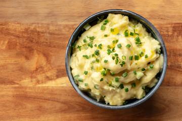 Pomme puree, a bowl of mashed potatoes with herbs, shot from the top on a rustic wooden background with copy space