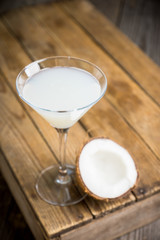 Sweet coconut cocktail in martini glass on the wooden background. Selective focus. Shallow depth of field. 
