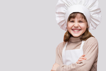 Children cook. Happy little girl in chef uniform holds rolling pin isolated on white background.