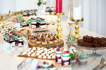 Delicious wedding reception candy bar dessert table full with cakes and sweets and a candles