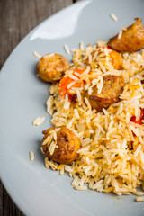 Roasted rice with grilled sausages and bell pepper on the wooden table. Selective focus. Shallow depth of field.