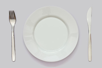 empty white plate, knife and fork on white table. Table setting