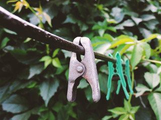 Linen clothespins in the yard. Plastic linen clothespin on old rope on green background. Many multi-colored plastic clothespins. Linen clothespins on the counter. Rainy summer day. Top view.