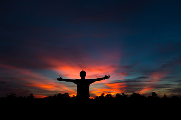 Fototapeta na wymiar Silhouette of a male holding hands at sunrise.