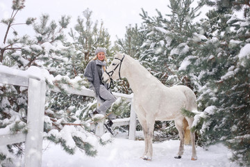 Naklejka premium Young happy smiling attractive blond woman with horse, overcast winter day
