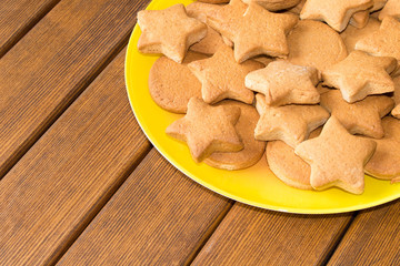 Top view of freshly made cookies in a yellow plate on a wooden table. Close up