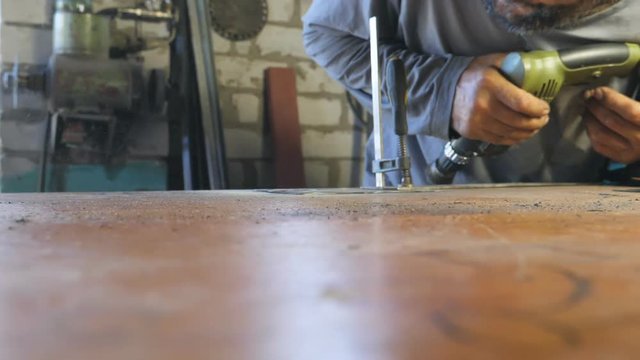 Mechanic blows away dust and dirt after checks detail during work. Man works in his garage or workshop. Hard work concept. Slow motion Close up Dolly shot