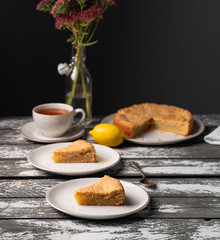 a slice of homemade lemon cake, on a rustic wooden backdrop, dark background