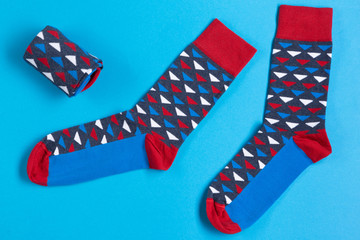 two multi-colored socks are located on a blue background, a folded sock lies next to it