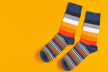 two multi-colored striped socks lie on a yellow background