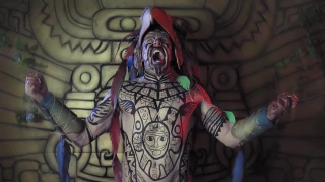 Aztec warrior with body paint on his body, is screaming and shaking before the battle