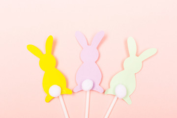 Obraz premium Easter background. Colorful bunnies shape cake toppers on pastel pink background. Flat-lay, top view. Copy space for your text.