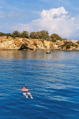 view from the yacht to a masked man sailing towards the wild coast of island Crete