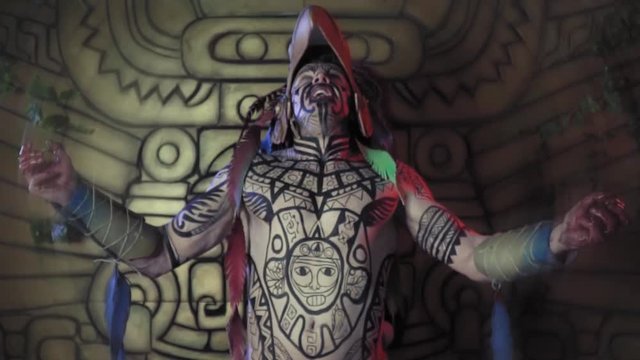 Creepy aztec warrior getting ready before the battle, screaming and shaking with his arms spread