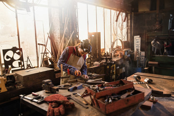 A female craftsman in her workshop working on a metal piece 