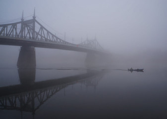Mystic view of the old Volga bridge in thick morning fog. Russia, Tver