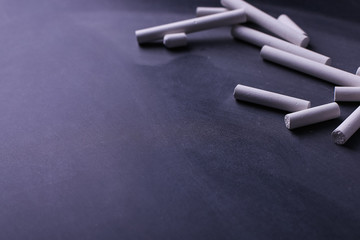 Naklejka premium Crayons lie on a black chalkboard, copy space. The concept of school, education and childhood.