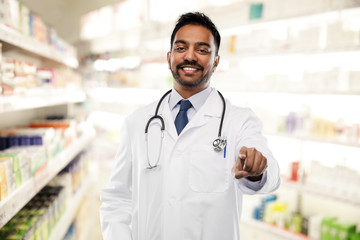 medicine, pharmacy and healthcare concept - smiling indian male doctor or pharmacist in white coat...
