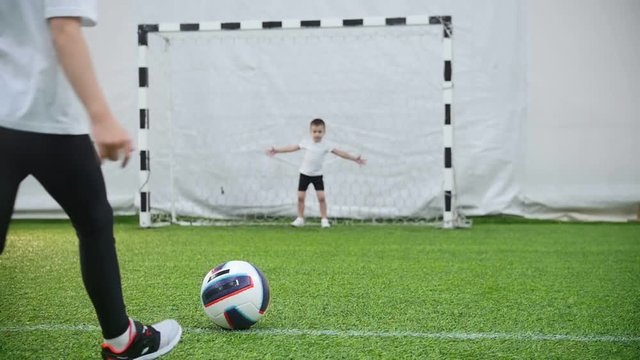 Kids playing football. A little girl kick the ball but the gatekeeper protects the gates