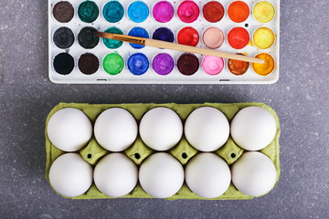 White eggs, paints and tassels, preparation for coloring for Easter.
