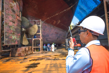 Stevedore, controller, Port Master, surveyor inspect the bulk head of commercial cargo ship in floating dry dock, recondition of overhaul repairing and painting, sand blasting in dry dock yard