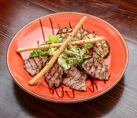 Pork meat grilled with fresh vegetable salad on a white plate.