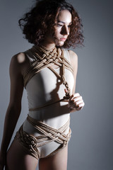 Young cute sexy sensual brunette woman female adult in beige bodysuit desires sexual tying shibari...