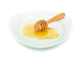 Wooden honey dipper with honey white plate on white background