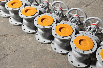 Several new gray valves, for water or gas, lie on the floor at the factory. The valves are gray for...