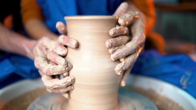Hands of young couple in love making clay jug on potter's wheel. Sensual footage of people on romantic date. Pottery training, artwork concept. Slow motion.