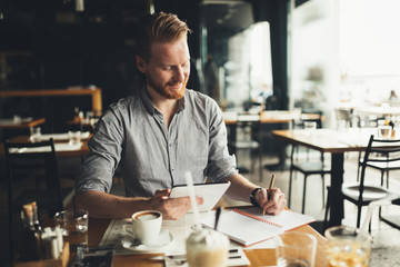 Fototapeta na wymiar Businessman taking notes in cafe