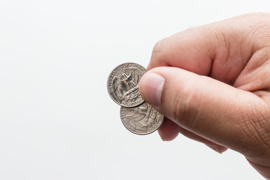 Male hand holding two quarter dollar coins, white background