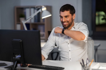 business, technology and time management concept - happy businessman using voice command recorder on smart watch at nigh office