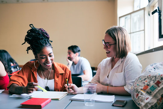 Happy female students studying together in language school