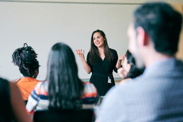 Smiling teacher explaining students in classroom